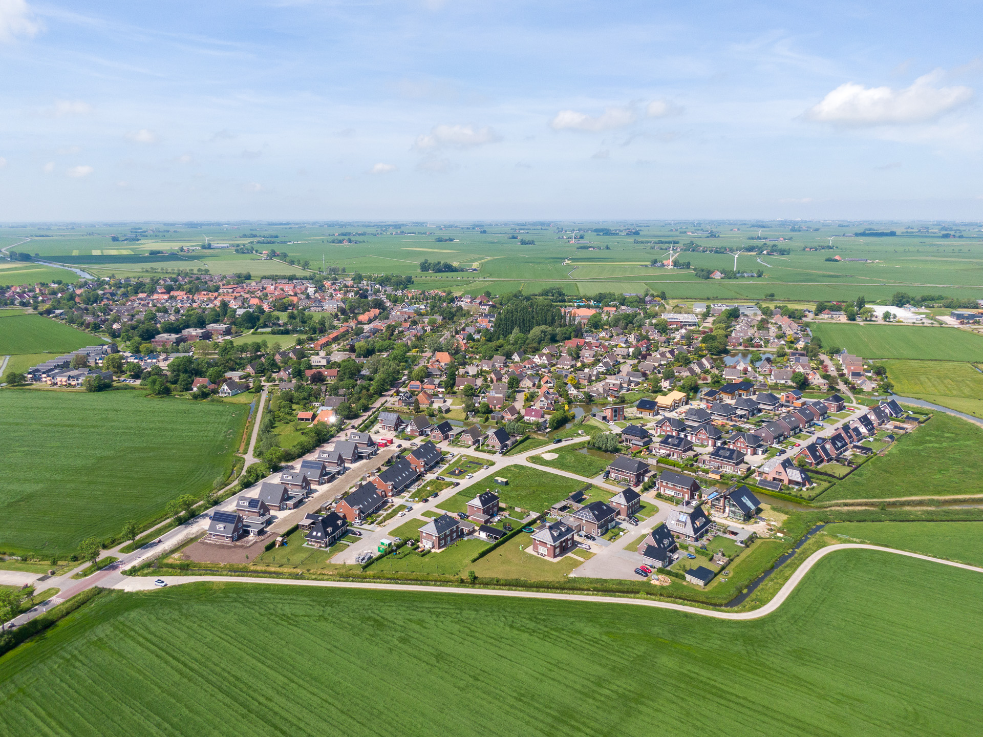 Een dorp met weilanden in de omgeving vanuit de lucht